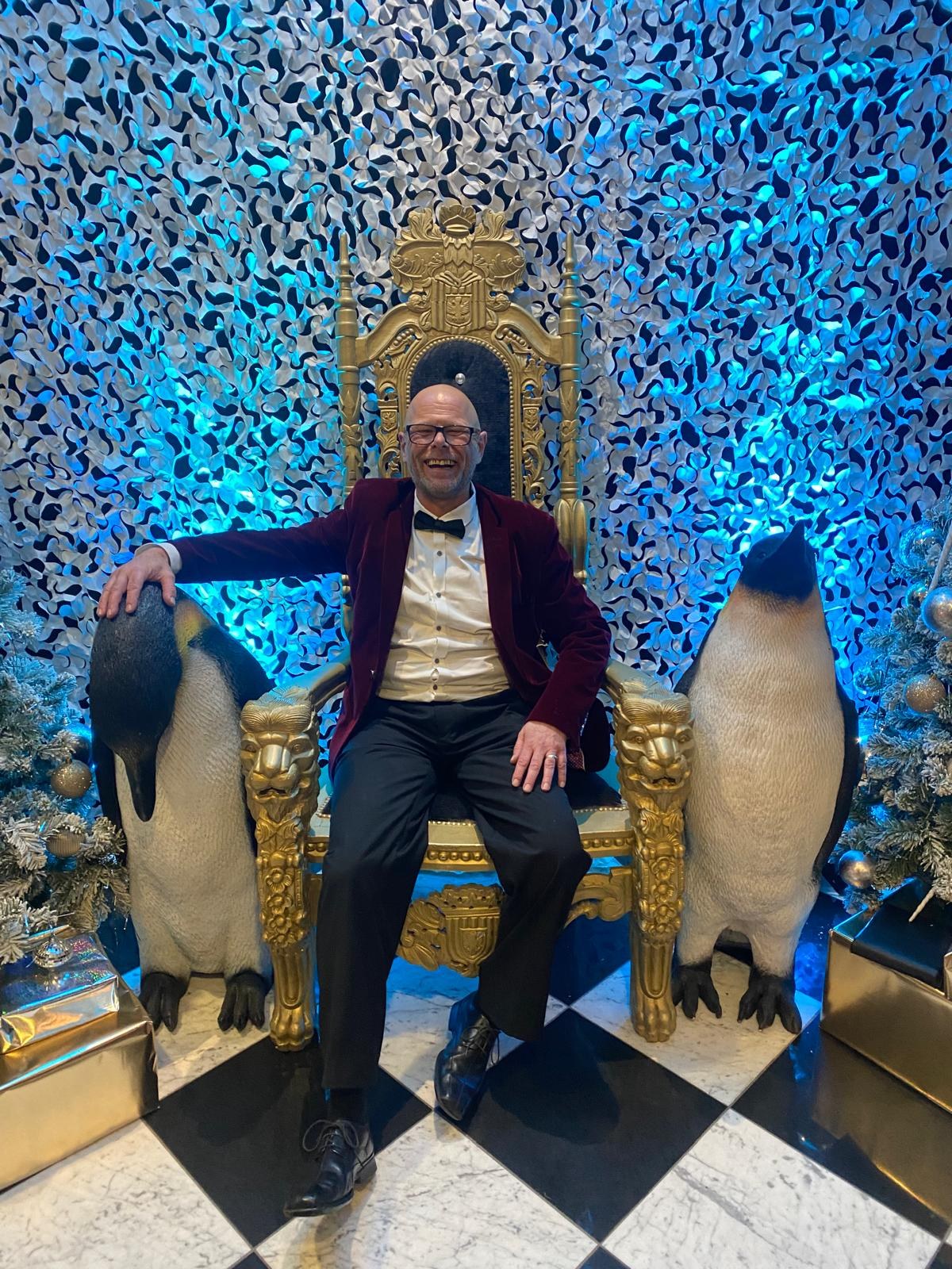 Tricky on a golden throne between two penguins